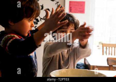 Boys playing with flour in mixing bowl Stock Photo