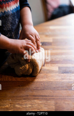 Toddler kneading dough on kitchen worktop Stock Photo