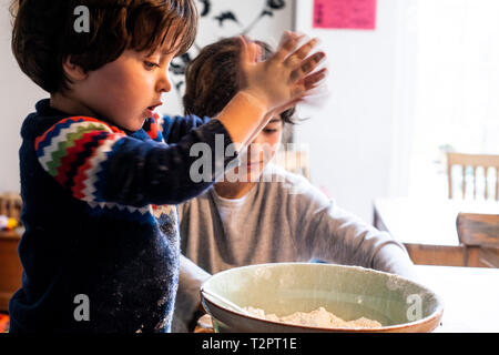 Boys playing with flour in mixing bowl Stock Photo
