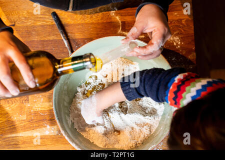 Woman pouring oil into flour in mixing bowl Stock Photo