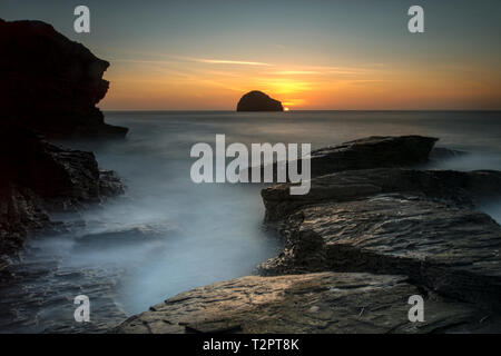 The sun setting just before twighlight  behind Gull rock on the north cornwall coast at Trebarwith Strand. Stock Photo