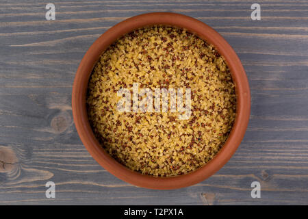 bowl of raw bulgur and quinoa on wooden table background Stock Photo