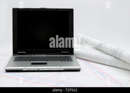 Computer with architectural plans lying on table Stock Photo