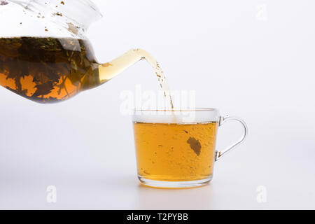 Glass teapot pouring green tea into cup isolated on white Stock Photo