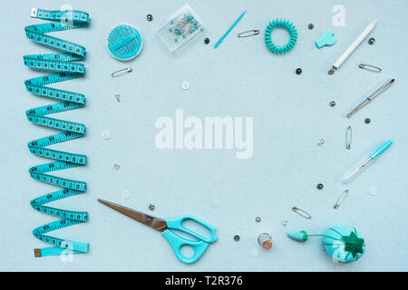 Sewing kit on a blue background. Scissors, tape, pins, needles, ripper, buttons, buttons thimble weight crayon pencil View from above Stock Photo