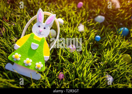 Happy Easter. Easter eggs hidden in spring grass. Bunny shaped basket with eggs left in garden Stock Photo