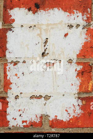 Peeling remains of a white paper poster stuck to a red brick wall background with copy space. Stock Photo