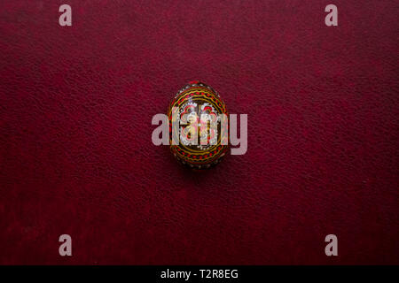 Easter black egg  with a homemade pattern. Closeup view on empty magenta leather background, place for your text. Minimal composition. Stock Photo