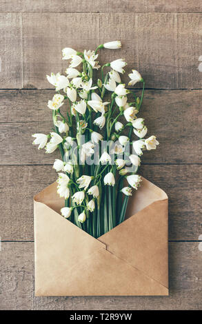bouquet of fresh snowdrops in the mail envelope on a wooden background Stock Photo