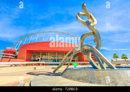 Doha, Qatar - February 21, 2019: Olympic rings monument at Aspire Zone in Doha Sports City with Khalifa National Stadium on background. Stock Photo