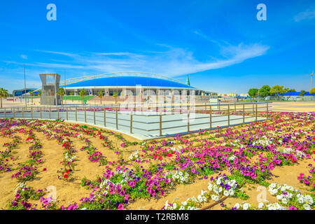 Doha, Qatar - February 21, 2019: flower beds and Aspire Dome on background. Aspire Academy is a sporting academy for youth, located in the center of A Stock Photo
