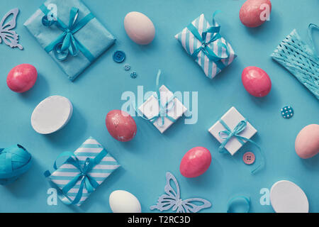Easter flat lay in white and pink on blue mint paper background. Geometric pattern with colored eggs, gift boxes and spring decorations. Stock Photo