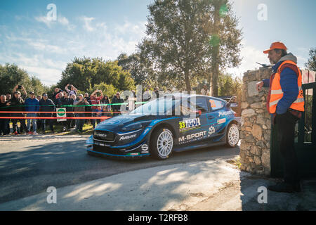 Regino, Corsica - 31st March 2019. Spectators and a marshall watch as E. Evans & S. Martin take a corner during Special Stage SS13 between Regino and  Stock Photo