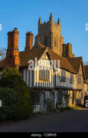 View of a row of medieval half timbered houses in the village of Stoke By Nayland with the local church tower rising behind them, Suffolk, England, UK Stock Photo