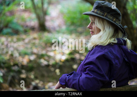 Shorne, Country Park, Kent. UK. A middle aged woman enjoys a rest on a bench while on a countryside walk. Stock Photo