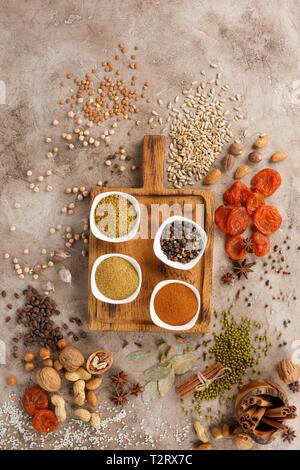 Dried fruits spices cereals and nuts organic healthy snacks on a textural background. Decorative board. Frame for the text.Copy space. Flat Lau. Stock Photo
