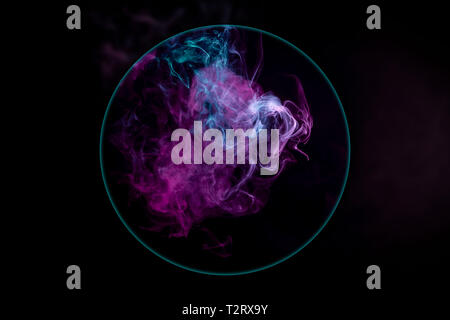 Close-up  frozen abstract movement of  explosion smoke multiple colors blown under a magnifying glass on black background. Background from the smoke o Stock Photo