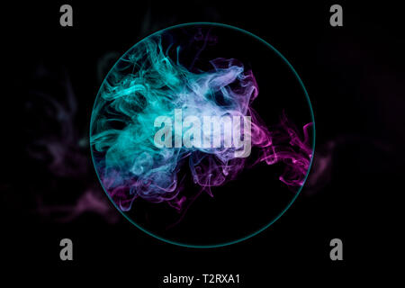 Close-up  frozen abstract movement of  explosion smoke multiple colors blown under a magnifying glass on black background. Background from the smoke o Stock Photo