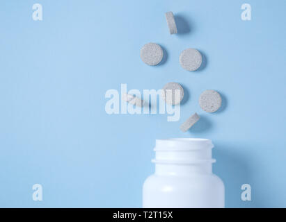 Medication bottle and pills spilled on blue pastel coloured background with place for text. Medication and prescription pills background Stock Photo