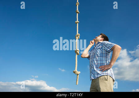 A caucasian man looking at a knotted rope Stock Photo