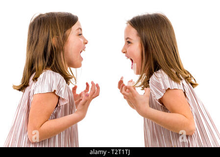 Identical twin girls are looking at each other and smiling. Concept of family and sisterly love. Profile side view of twin sisters in dresses looking  Stock Photo