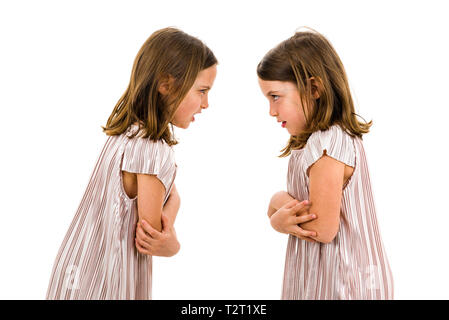 Identical twin girls sisters are arguing yelling at each other. Angry girls are shouting, yelling and arguing with emotional expression on faces. Fron Stock Photo