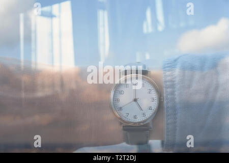 Reflection of a Caucasian man wearing a wrist watch showing the time 5:00 Stock Photo