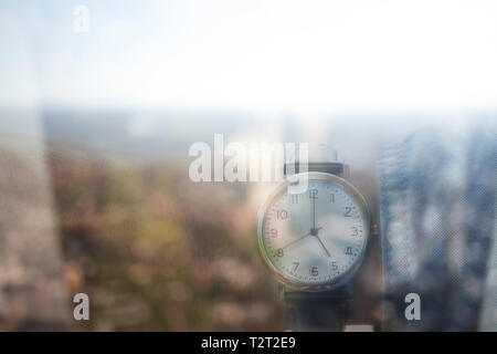 Reflection of a Caucasian man wearing a wrist watch showing the time 5:00 Stock Photo
