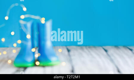 Abstract bokeh and blurred colorful background of children's rain boots / wellies with bokeh agaisnt a blue background with room for copy space. Stock Photo