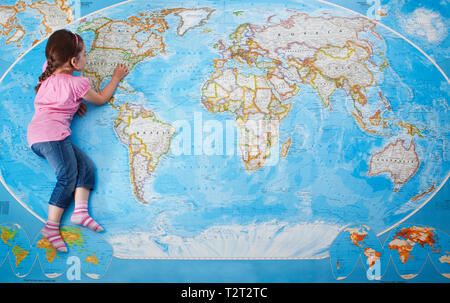 Top view of a young caucasian girl laying on a map of the world Stock Photo