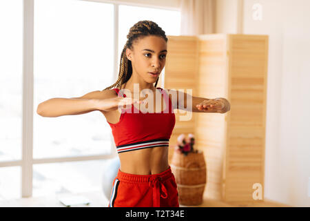 Shorts and top. Slim woman with nice abs wearing red shorts and top while doing exercises at home