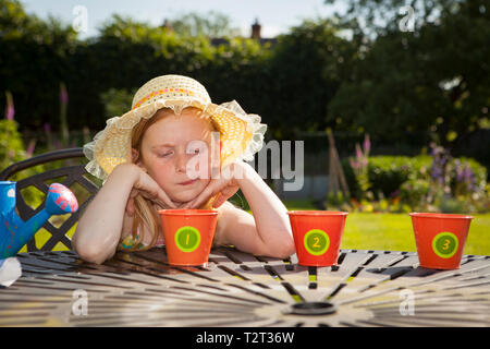 Pre teen caucasian girl looking at flower pots in a garden Stock Photo