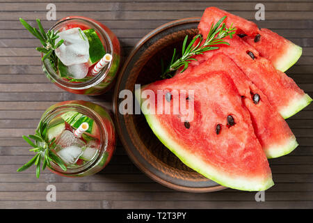 Refreshing summer watermelon drink with rosemary, watermelon slices  on a plate. Watermelon and rosemary infused water with ice. Concept of detox and  Stock Photo