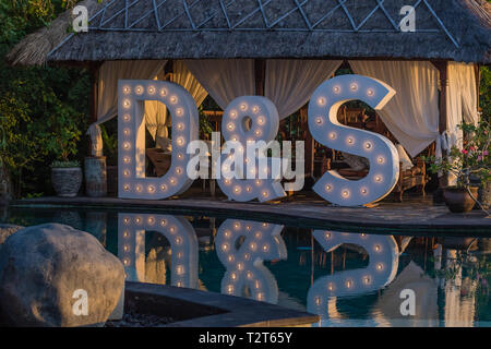 Big wedding light up letters D & S near the pool with reflection on the water. Festivity, wedding, party. Stock Photo