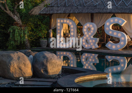 Big wedding light up letters D & S near the pool with reflection on the water. Festivity, wedding, party. Stock Photo