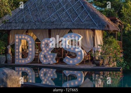 Big wedding light up letters D & S near the pool with reflection on the water. Festivity, wedding, party. Stock Photo