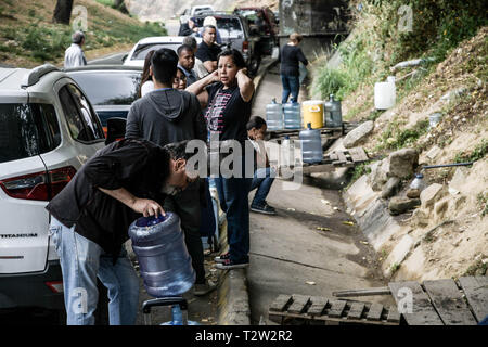 People collect water released through a pipe that comes from the mountain during a water shortage in the capital. A new blackout and water shortage hits Venezuela today which keep savaging the country economy as well as paralyzing the oil industry which cost the country around $200 million USD a day according to experts. Stock Photo