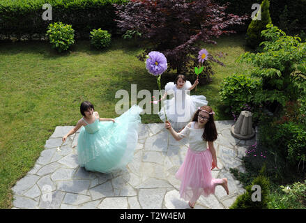 little girls dressed as princesses playing in the garden Stock Photo