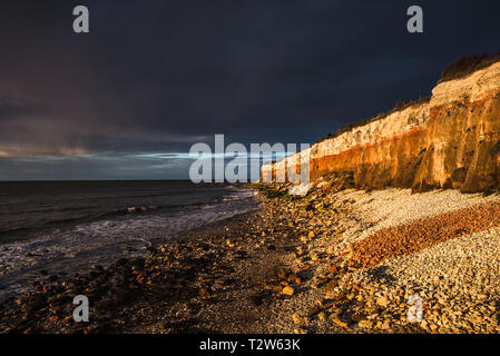 Hunstanton Cliffs at sunset with dark stormy sky, on Norfolk coast, where white chalk overlays red limestone in a colourful formation. England, UK. Stock Photo