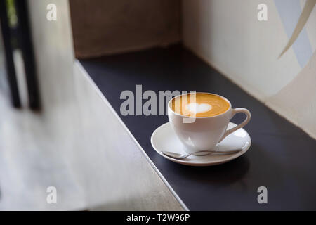 White cup of tasty cappucino with love art latte. Valentine's concept. Black stone backdrop. Stock Photo