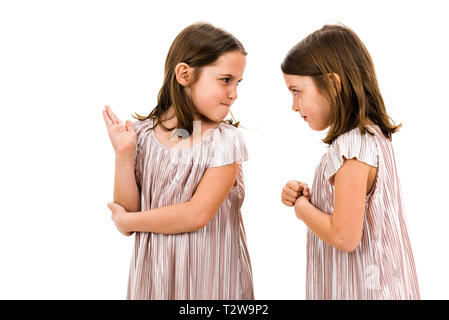 Identical twin girls sisters are arguing yelling at each other. Angry girls are shouting, yelling and arguing with emotional expression on faces. Fron Stock Photo