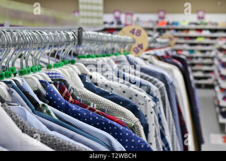 Elegant shirts on hangers in the store blurred. On the eve of Black Friday. Background for design from a department store. Stock Photo