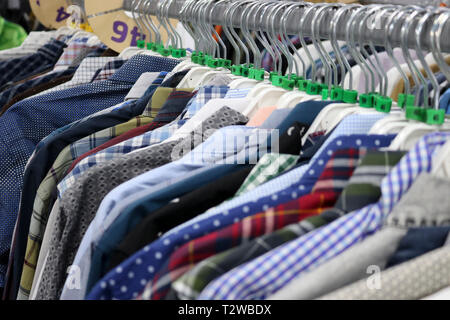 Elegant shirts on hangers in the store blurred. On the eve of Black Friday. Background for design from a department store. Stock Photo
