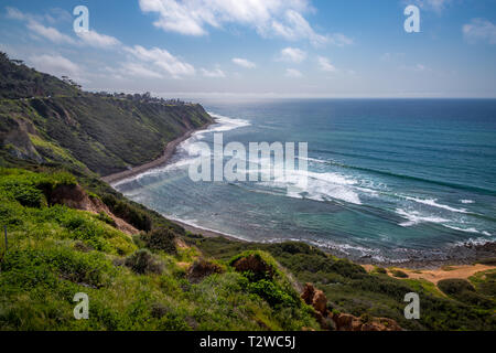 Scenic coastal view of tall cliffs of Bluff Cove covered with vegetation on a sunny spring day with  turquoise colored water and rocky beach, Blufftop Stock Photo