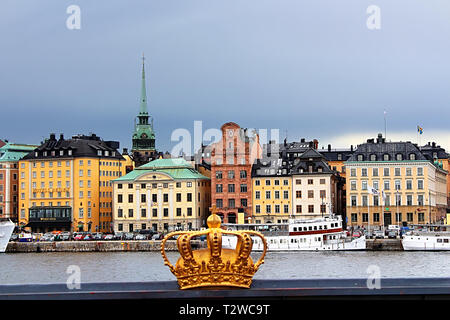 STOCKHOLM, SWEDEN - AUGUST 12, 2013: Golden crown detail on bridge and Gamla Stan (Old town) Stock Photo