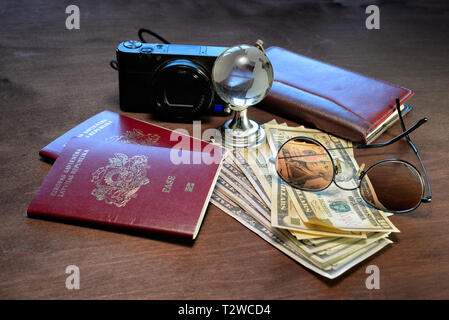 Sunglasses, a glass globe, passports, camera, notebook and money on a dark wooden background. Tourism concept. Stock Photo