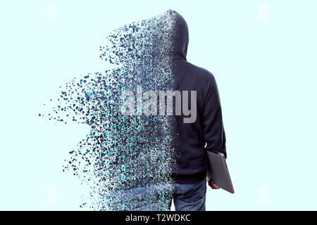 Back view of man in hood, hacker with laptop dispersing and disintegrating into particles of the binary code, concept of technologies and programming Stock Photo