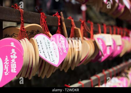 Ema, small wooden heart shaped plaques with handwritten wishes or prayers, at Kasuga Taisha shrine in Nara, Japan. Stock Photo