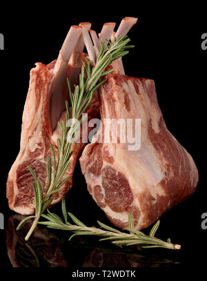 Raw rack of lamb with fresh rosemary isolated on black background Stock Photo