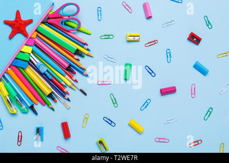 Colored pens, pencils, markers and other objects lie on a light blue background. 1 September concept postcard, teachers day. Top view, flat lay.
